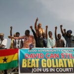 people with fists up holding a banner that says David can still beat Goliath; Join us in court!